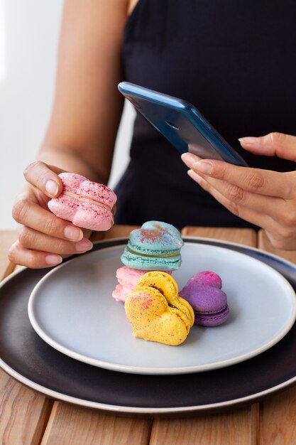 Woman taking photos of heart-shaped macarons on planes with smartphone
