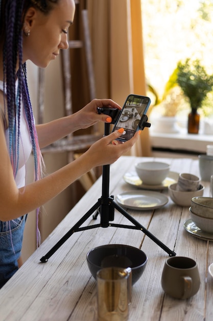 Женщина делает фотографии для своего бизнеса с керамической посудой