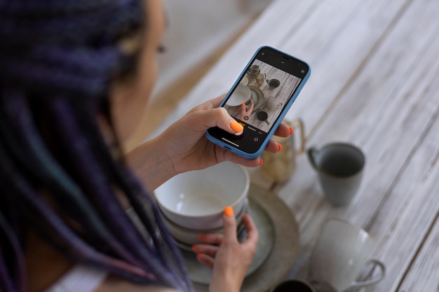 Free photo woman taking photos for her business with ceramic kitchenware