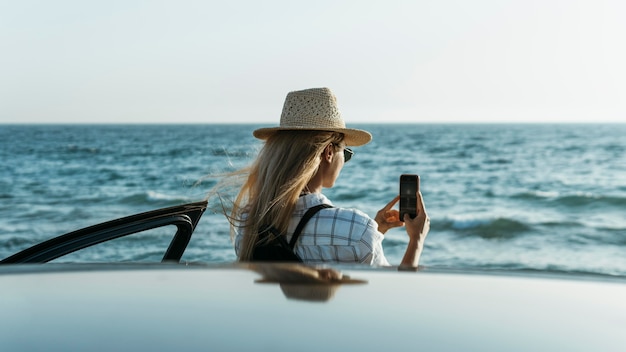 車で海の写真を撮る女性
