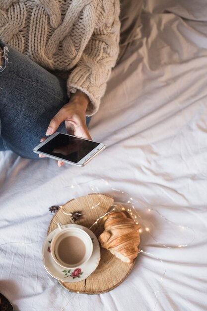 Woman taking picture of coffee and croissant