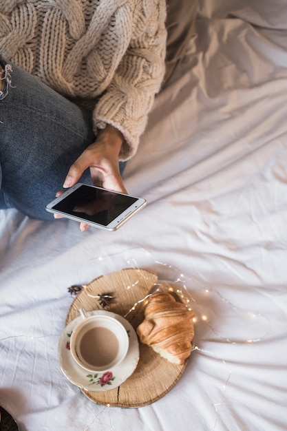 Woman taking picture of coffee and croissant