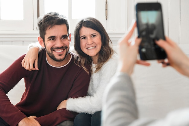 Woman taking picture of couple on couch 