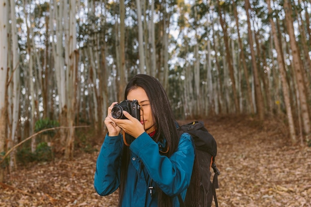 カメラで森の中で写真を撮っている女性