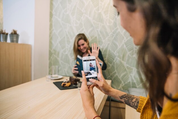 カフェで友人の写真を撮っている女性