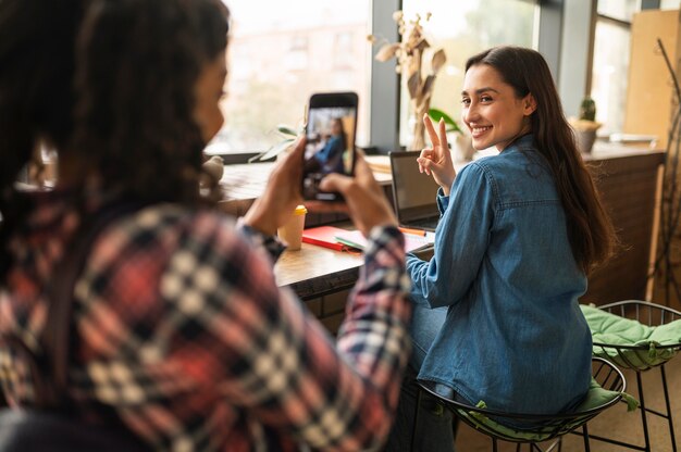 カフェで友達の写真を撮る女性