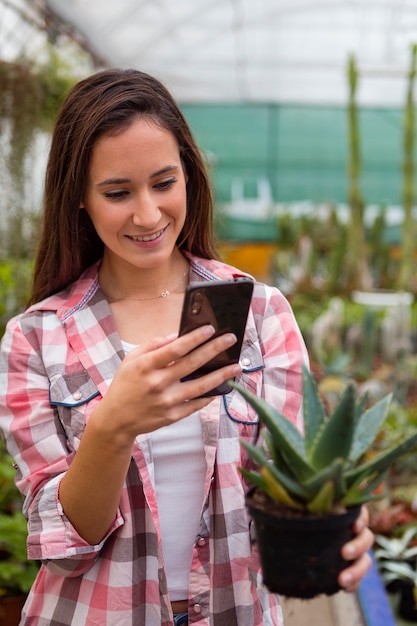 女性の温室で電話で植物の写真を撮る