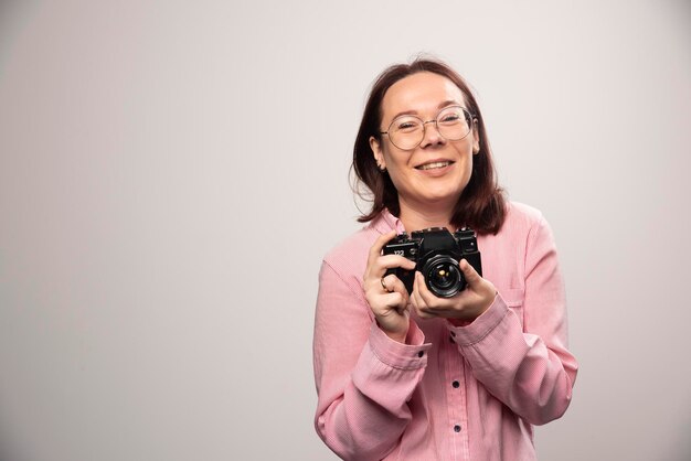 Woman taking a picture with camera on white. High quality photo