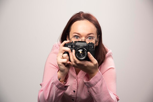 Женщина фотографирует с камерой на белом. Фото высокого качества
