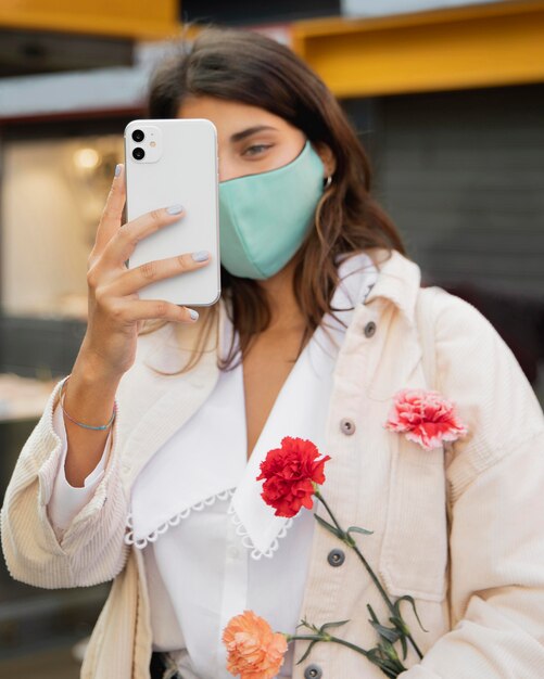 Woman taking a picture with smartphone while holding flowers