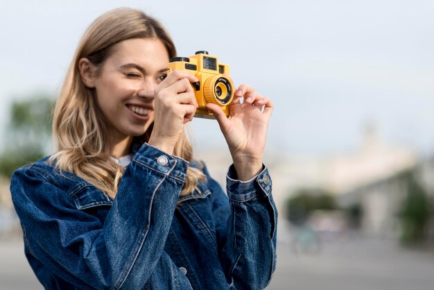 黄色のカメラで写真を撮る女性