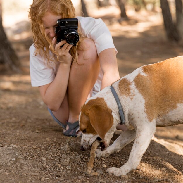 丸太を噛んでいる犬の写真を撮る女性
