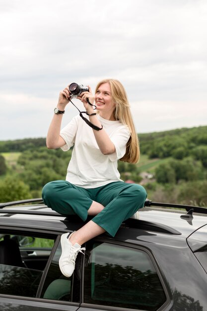 車に立っている間自然の写真を撮る女性