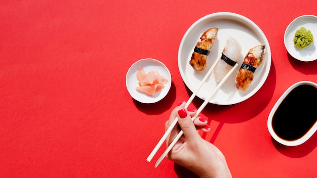 Женщина берет кусок суши из белой тарелки с суши