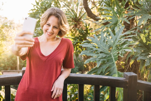 Foto gratuita donna che prende selfie vicino al recinto