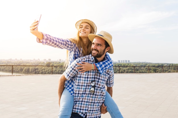 Foto gratuita donna prendendo selfie mentre avendo sulle spalle sul retro del suo ragazzo