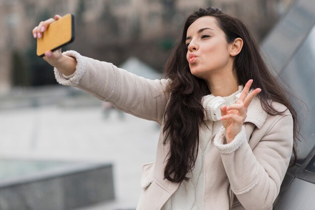 Woman taking selfie while making peace sign
