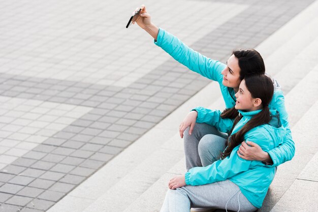 コピースペースを持つ娘と一緒に、selfieを取る女性