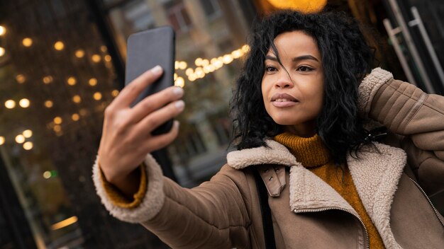 屋外でスマートフォンで自分撮りをしている女性