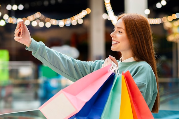Woman taking selfie with shopping bags