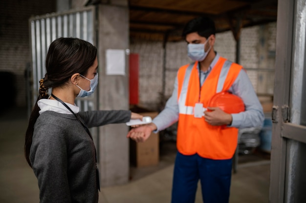 Free photo woman taking the temperature of a colleague