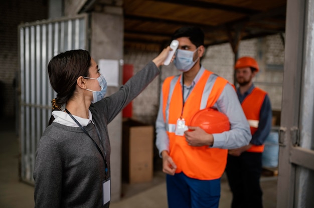 Free photo woman taking the temperature of a colleague