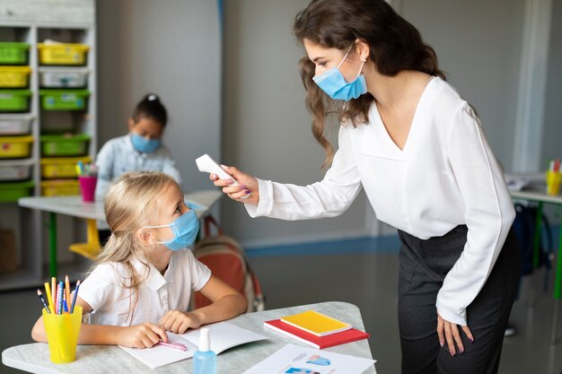 Woman taking the temperature of her student