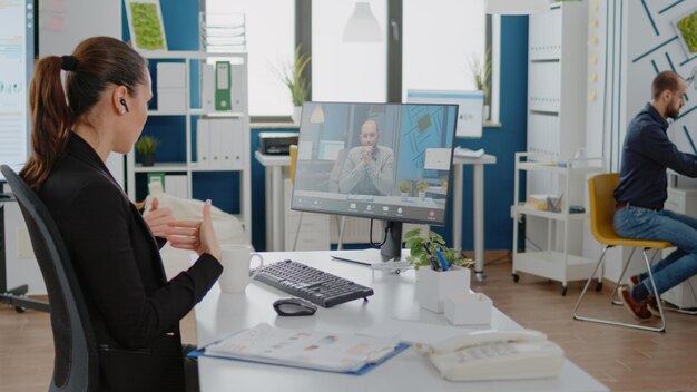 Woman talking to boss on video call communication for marketing strategy in corporate office. Entrepreneur using online conference for business meeting on computer with work manager