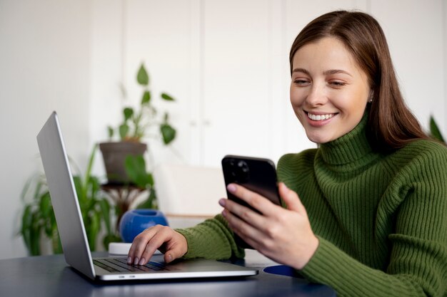 핸즈프리 기능을 사용하여 스마트폰으로 통화하고 노트북에 글을 쓰는 여성