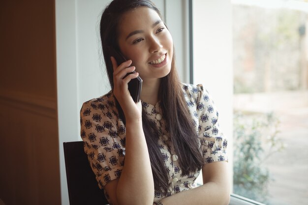 窓の近くで携帯電話で話している女性