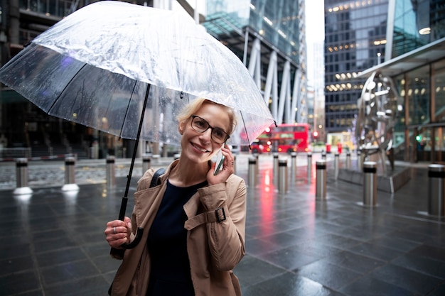 비가 올 때 밖에 있는 동안 전화 통화를 하는 여성 프리미엄 사진