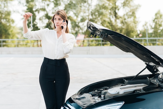 Foto gratuita donna che parla sul telefono e sull'automobile nera