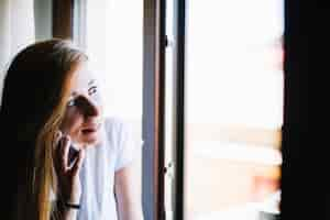 Free photo woman talking on phone near window