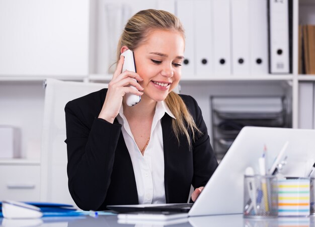 Женщина разговаривает по телефону в офисе