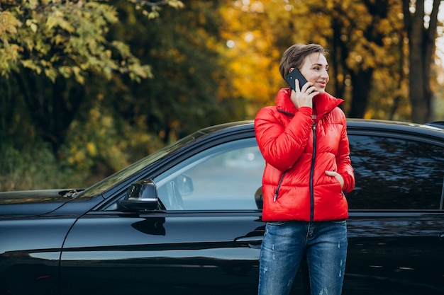 電話で話し、車のそばに立っている女性