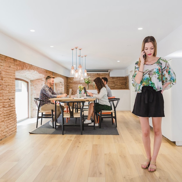 Free photo woman talking phone standing at office desk