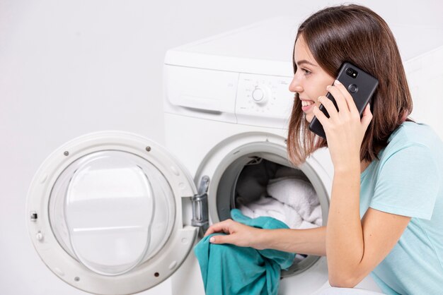 세탁을하는 동안 전화 통화하는 여자