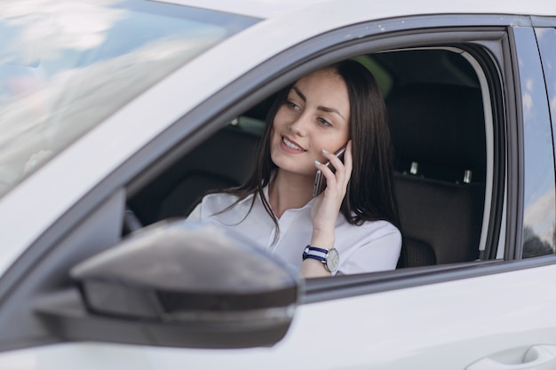 Женщина разговаривает по телефону во время вождения