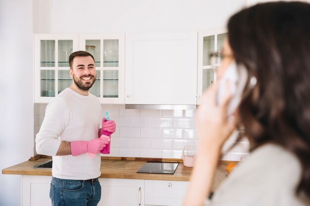 Woman talking on phone while man cleaning