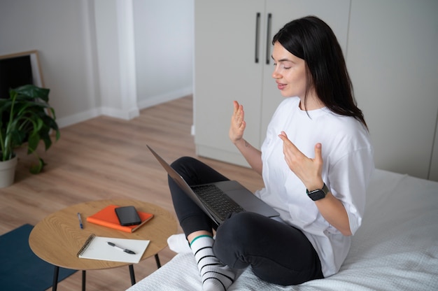 Foto gratuita donna che parla e usa il suo laptop a casa durante la quarantena