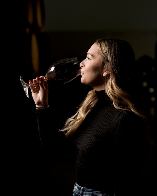 Woman tasting wine glass side view