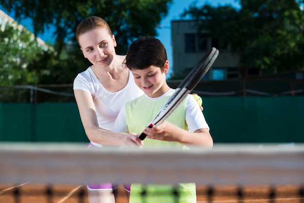 Woman teachekid how to play tennis