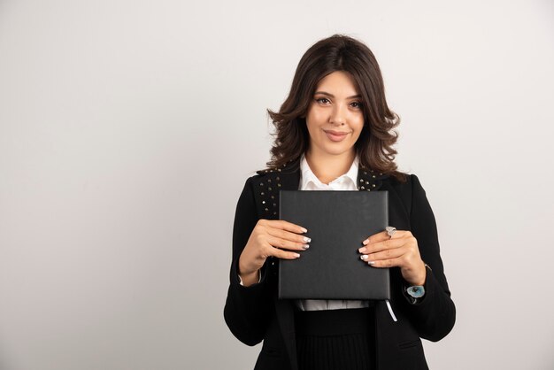 Woman teacher holding book with happy expression.