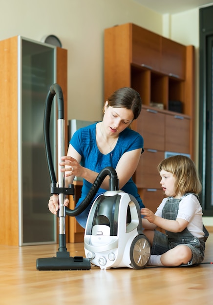 Woman teaches child to use the vacuum cleaner