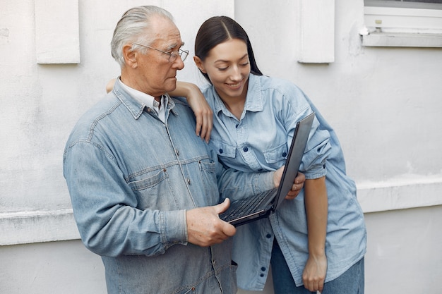 Woman teaching her grandfather how to use a laptop