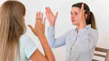 Free photo woman teaching other woman the sign language