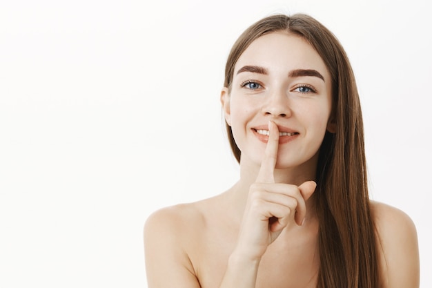 woman telling secret and making shh sigh, showing shush gesture with index finger over mouth