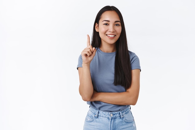 woman telling you number one rule, raising index finger and smiling as teaching or preaching something, pointing up