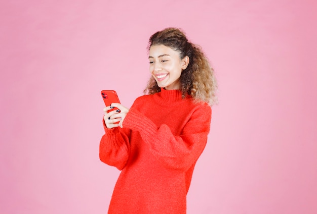 彼女の新しいスマートフォンでテキストメッセージを送って幸せを感じている女性。