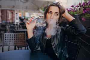 Бесплатное фото Женщина мышления с электронной сигаретой в руке
